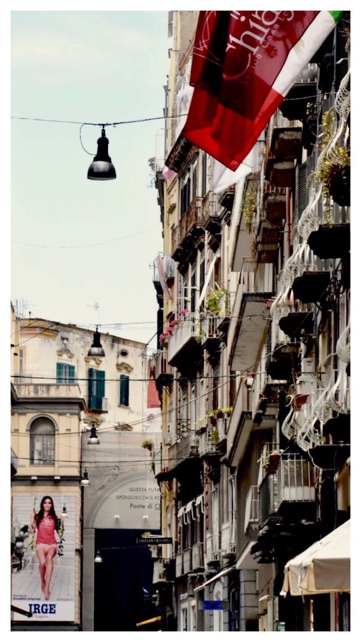 LOW ANGLE VIEW OF FLAGS HANGING ON CITY