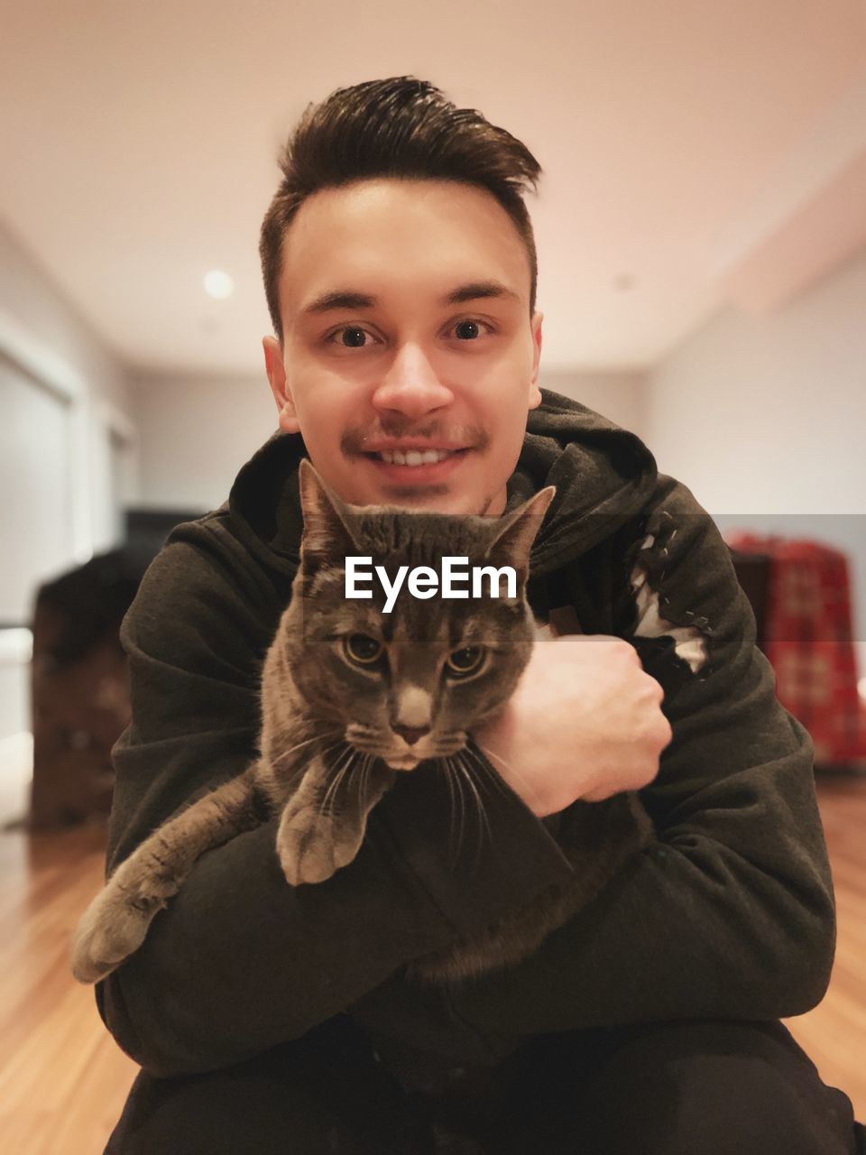 Portrait of young man holding cat at home