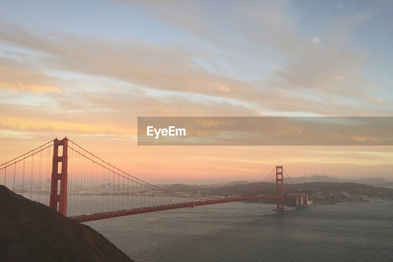 Golden gate bridge against cloudy sky at sunset