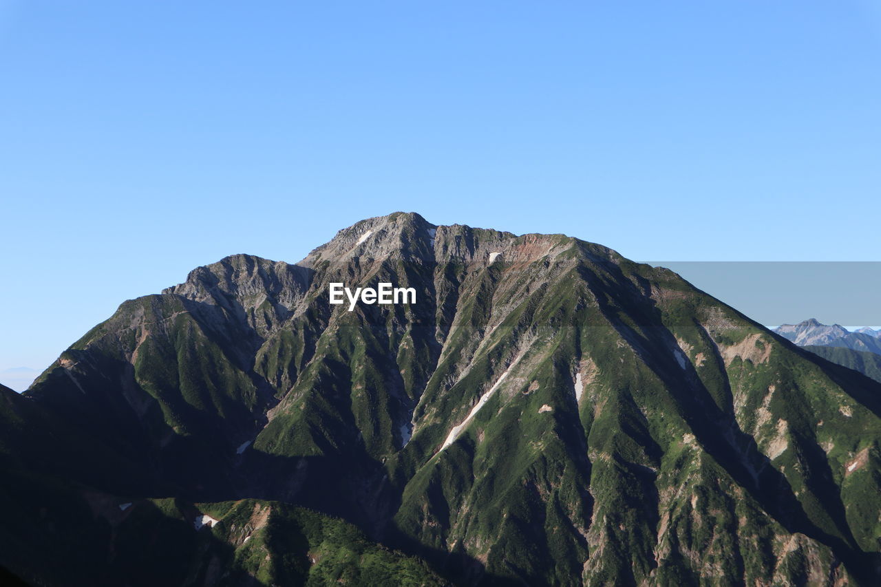 Low angle view of mountain against clear blue sky