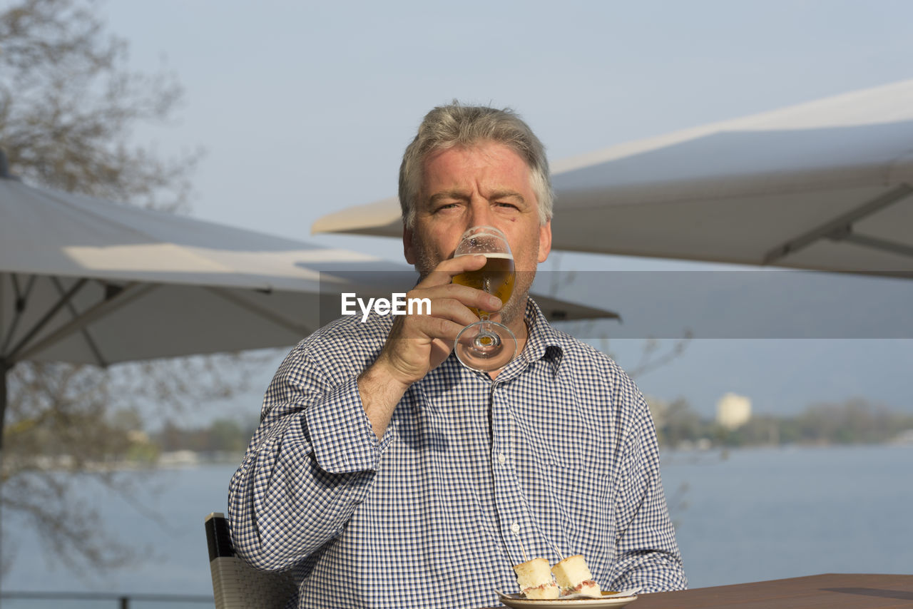 Portrait of senior man drinking beer at restaurant