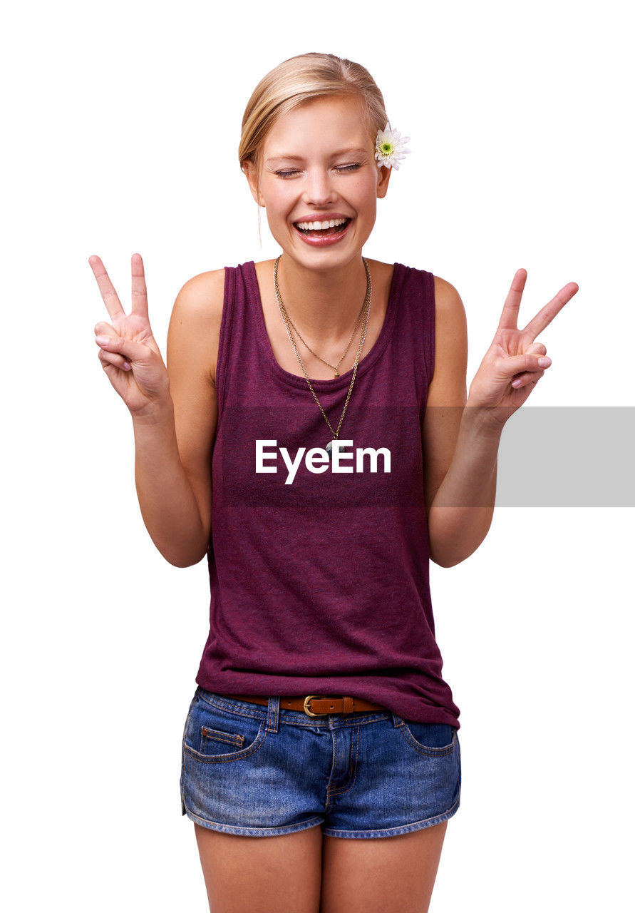 finger, smiling, emotion, happiness, gesturing, white background, one person, women, portrait, casual clothing, studio shot, cut out, cheerful, positive emotion, adult, young adult, hand sign, excitement, indoors, thumbs up, relaxation, laughing, looking at camera, smile, joy, teeth, communication, person, female, ecstatic, limb, hand, pointing, blond hair, fun, facial expression, standing, hand raised, human limb, front view, arm, shouting, clothing, showing, teenager, hairstyle, three quarter length, jeans, fashion, cute, enjoyment, carefree, mouth open, lifestyles, t-shirt, child, cheering, exhilaration, peace sign, vitality, human mouth, thin, shorts