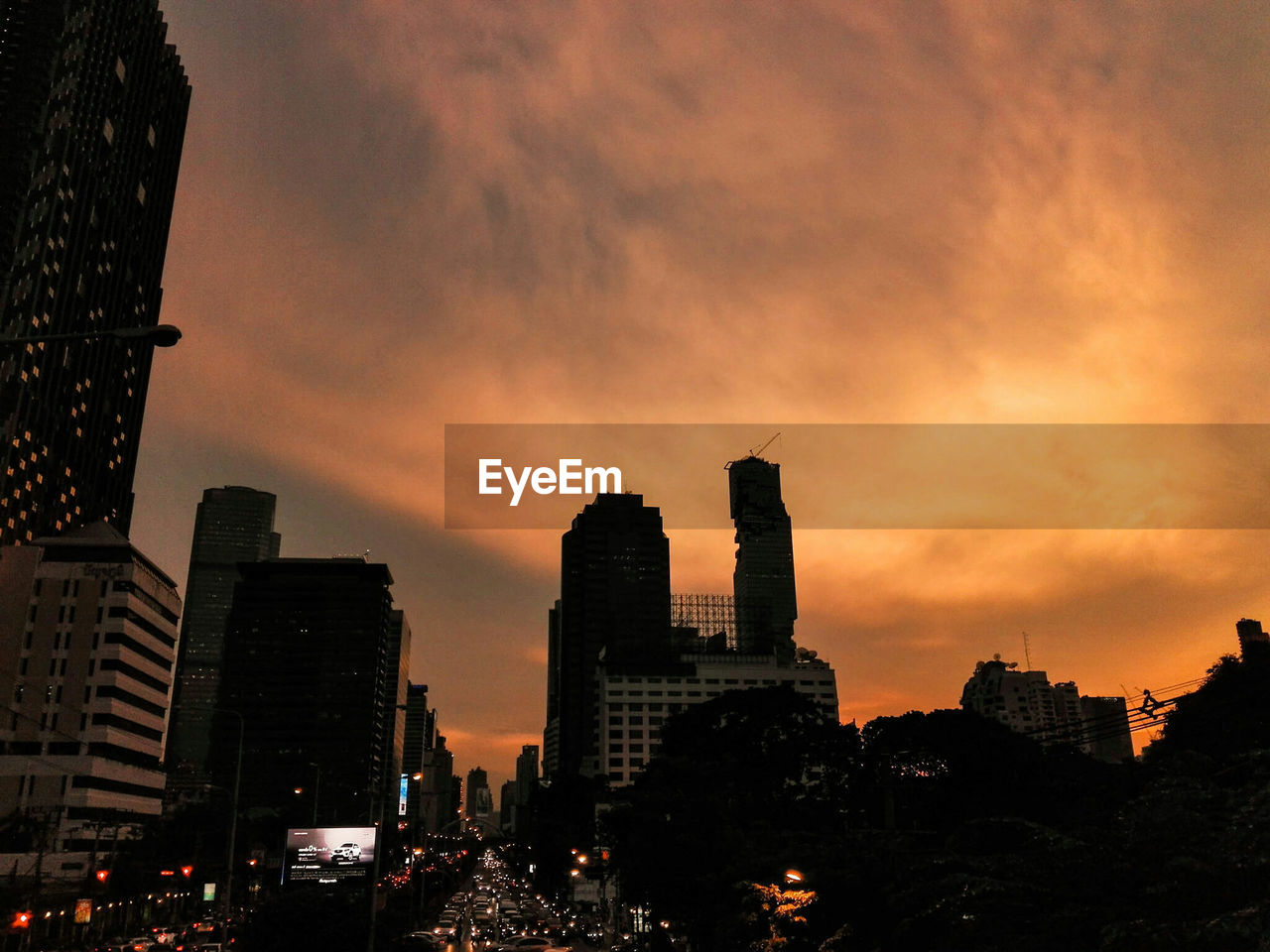 Silhouette of skyscrapers against cloudy sky during sunset