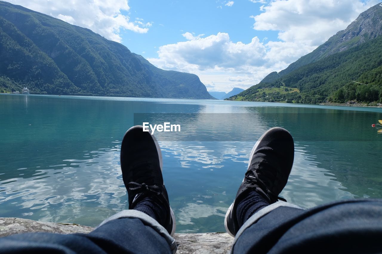 Low section of person by lake against mountains