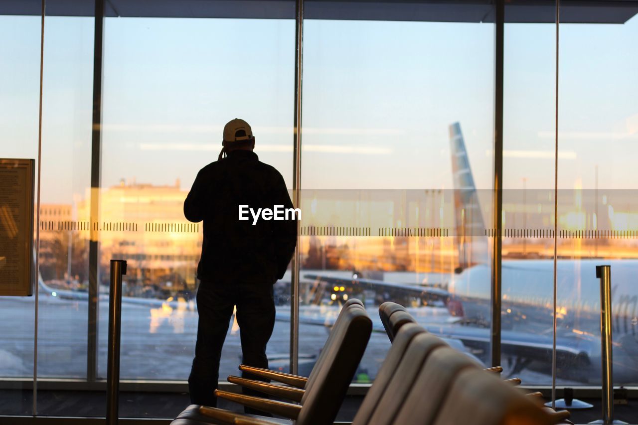 Man standing at airport against sky during sunset