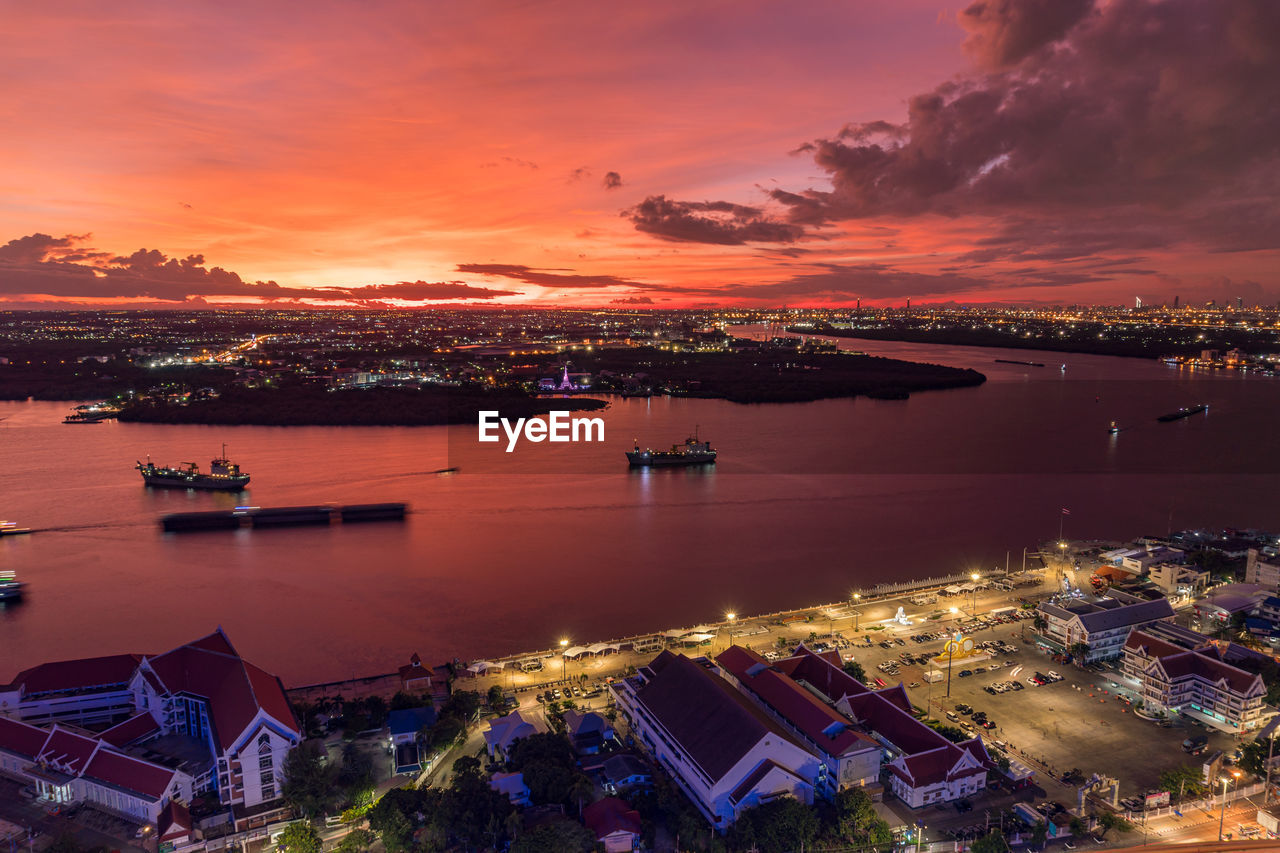 High angle view of illuminated harbor and buildings against sky during sunset