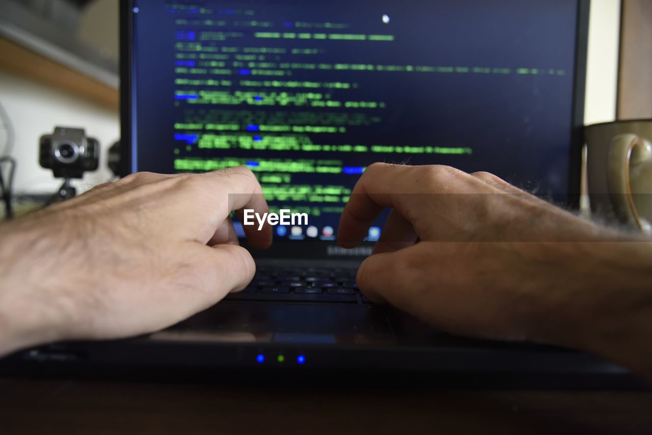 Cropped image of hands using laptop on table