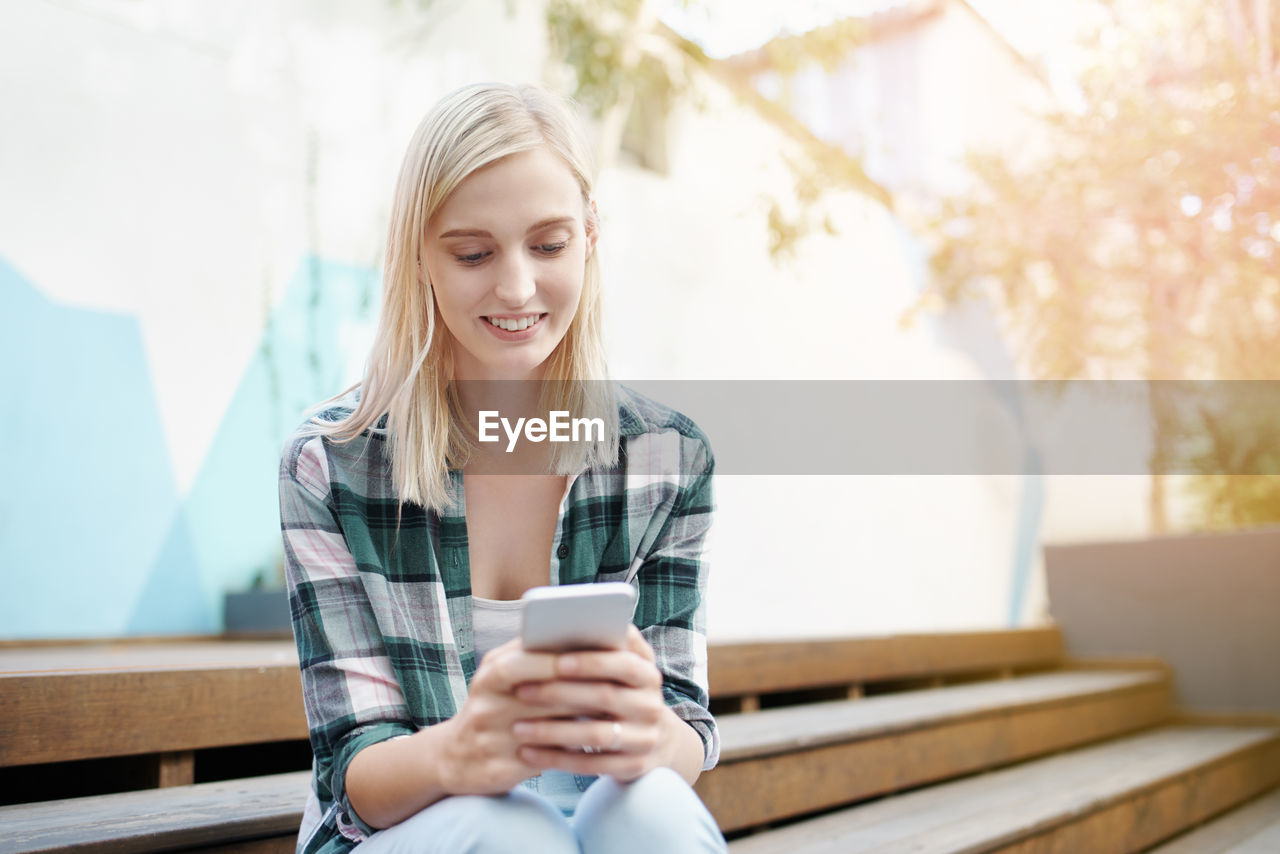 Smiling young woman using mobile phone