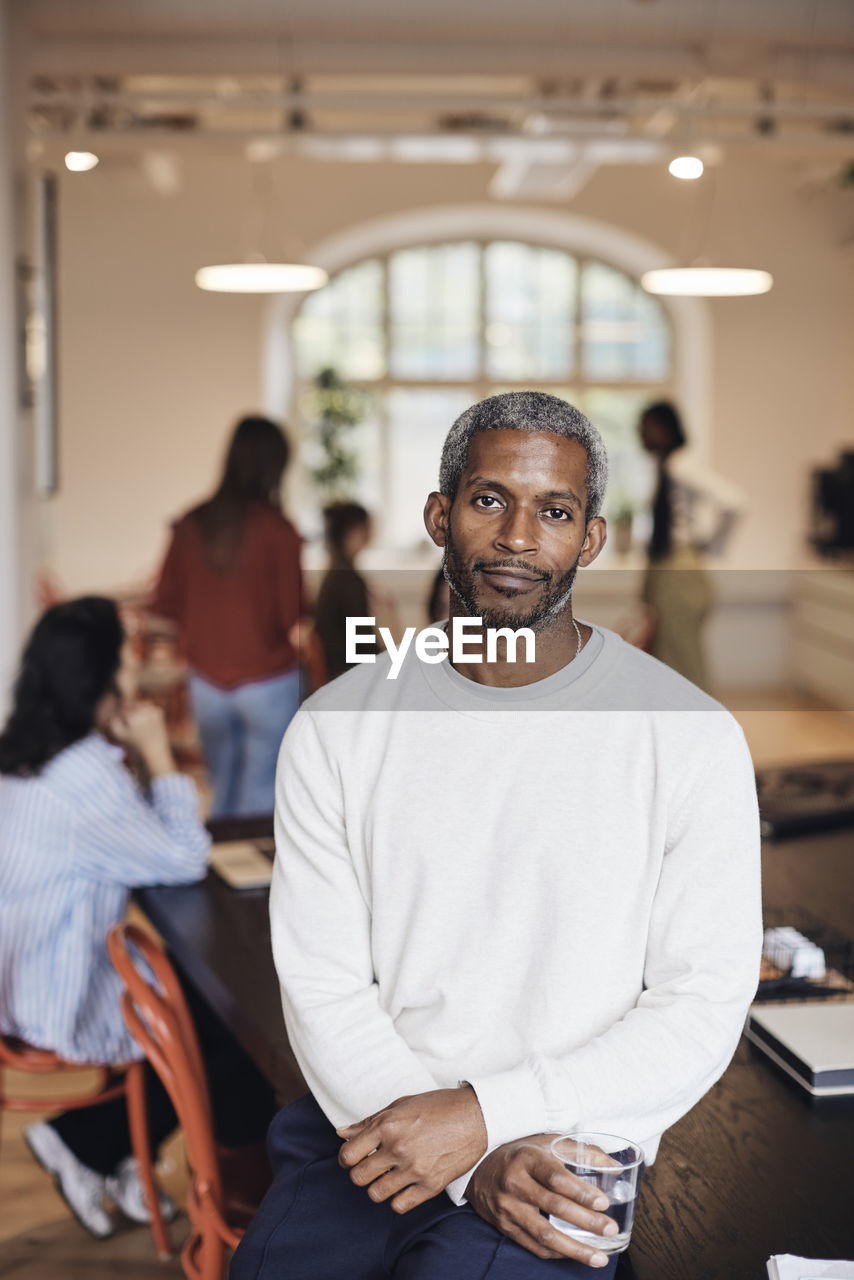 Portrait of male business professional sitting at desk in coworking office