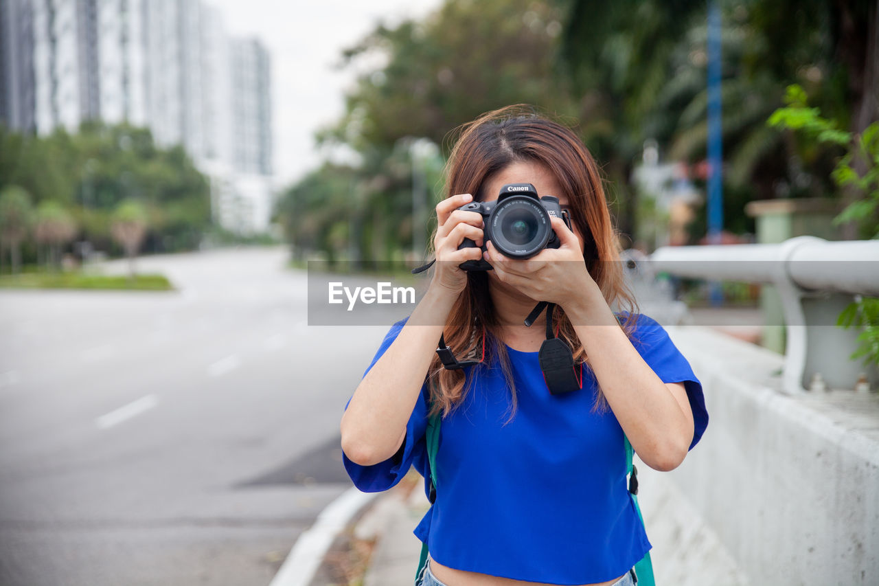 PORTRAIT OF BEAUTIFUL YOUNG WOMAN PHOTOGRAPHING ON STREET