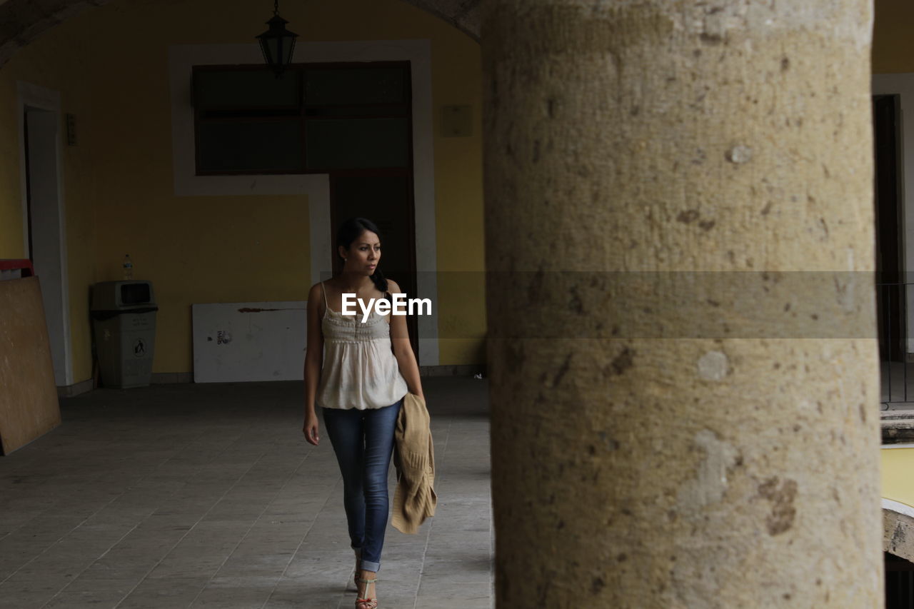 Full length of woman looking away while walking at corridor
