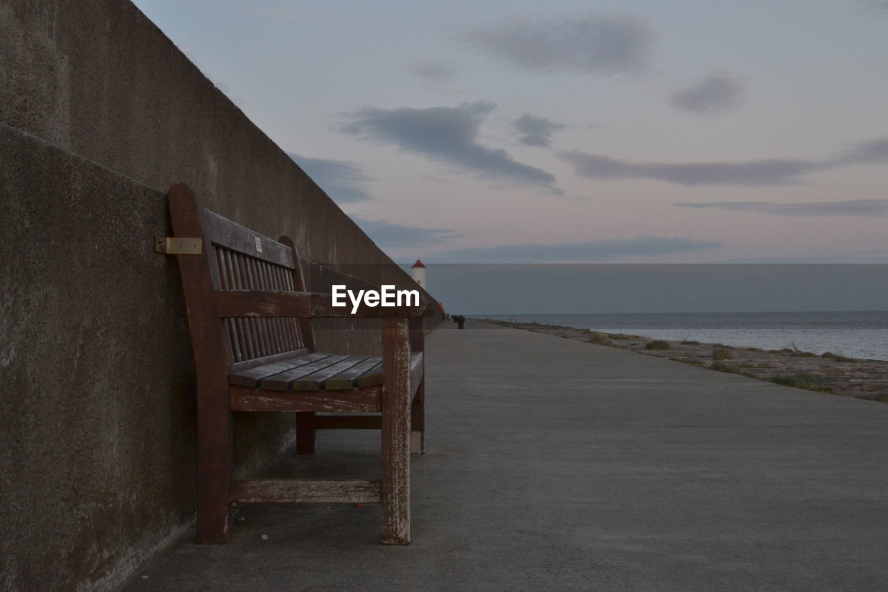 EMPTY BENCHES AT BEACH AGAINST SKY