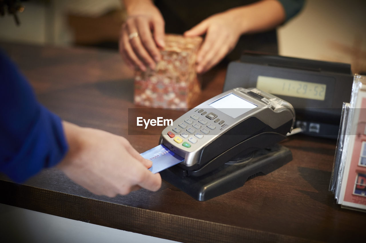 Cropped image of customer paying through credit card at checkout counter