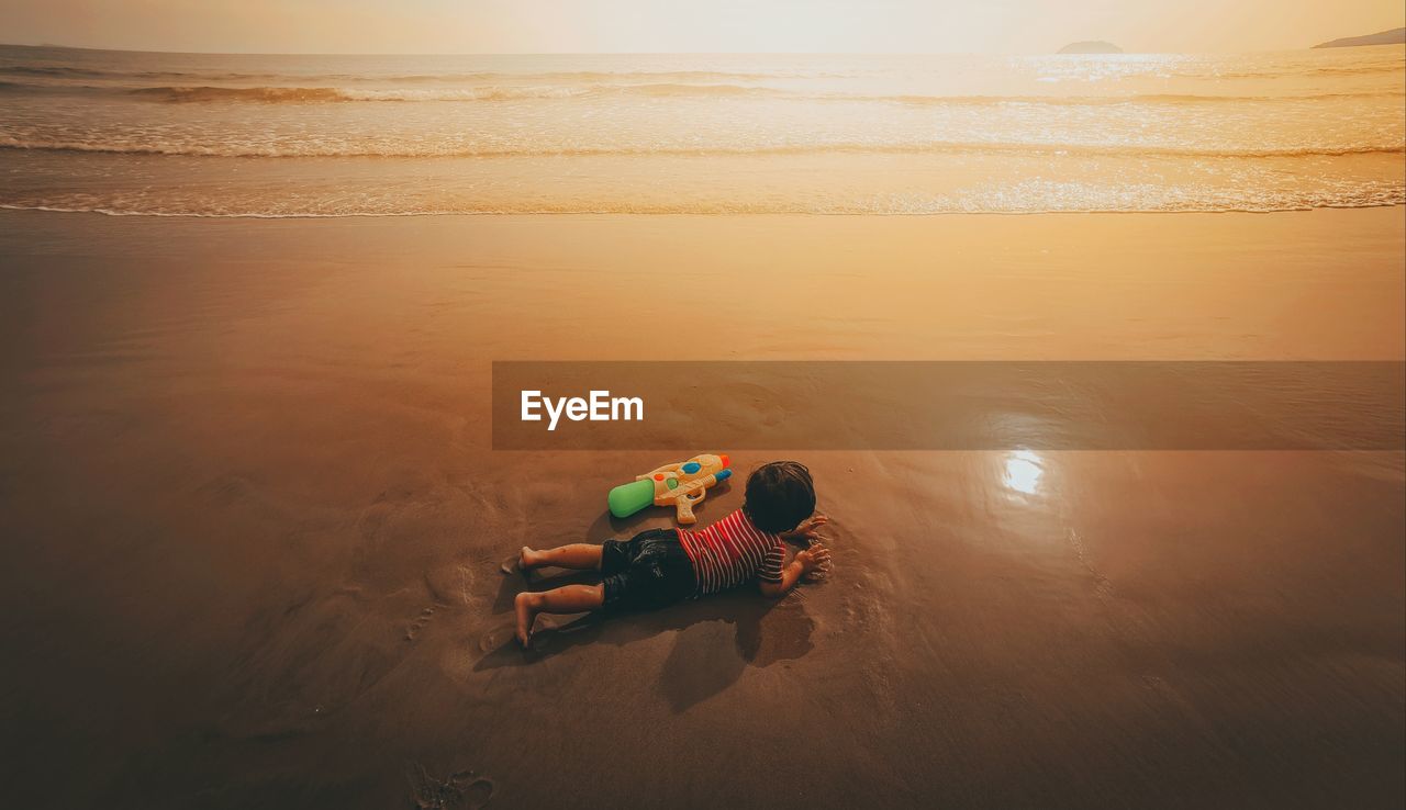 High angle view of man at beach against sky during sunset