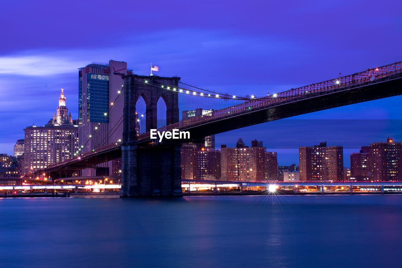 Illuminated bridge over river at night