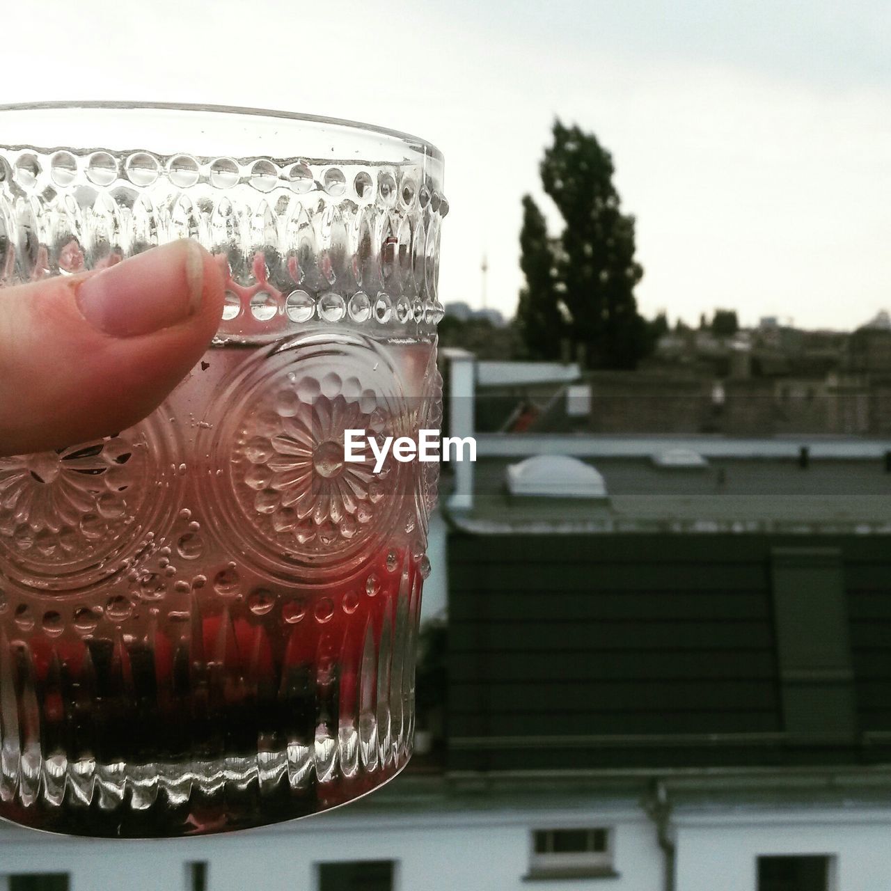 Hand holding drink in glass outdoors