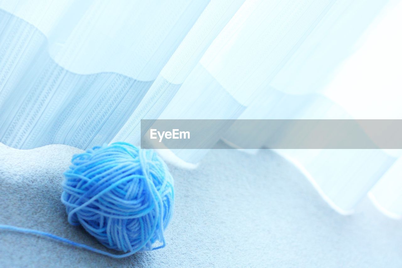 Blue ball of wool by curtain