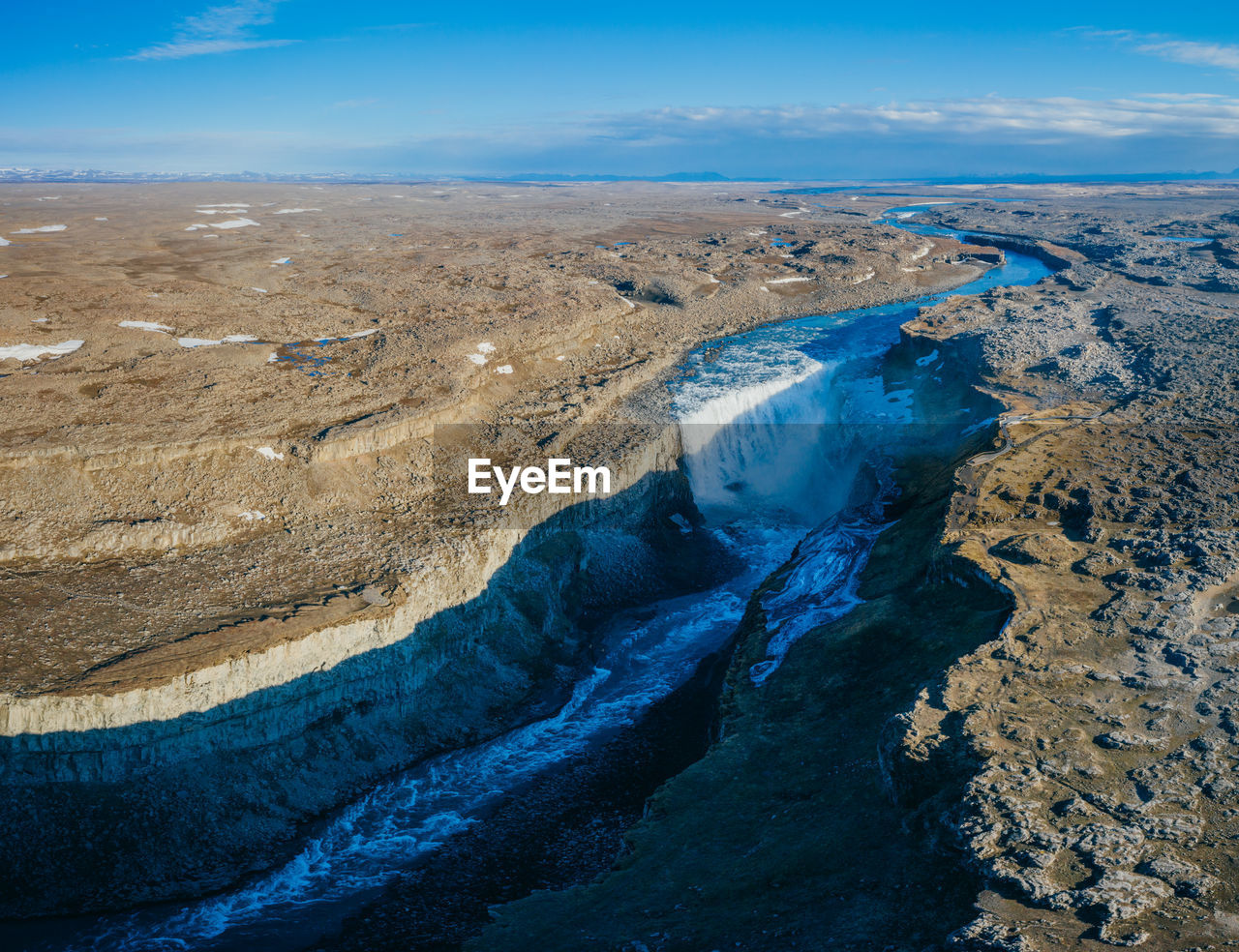 Aerial view of river flowing through land against sky