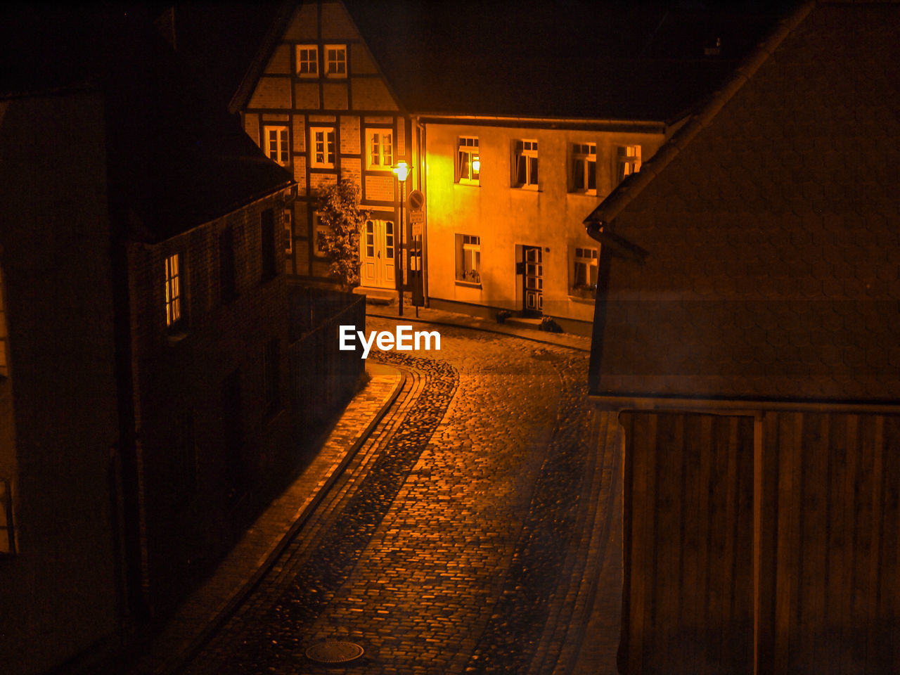 Empty road amidst illuminated buildings at night