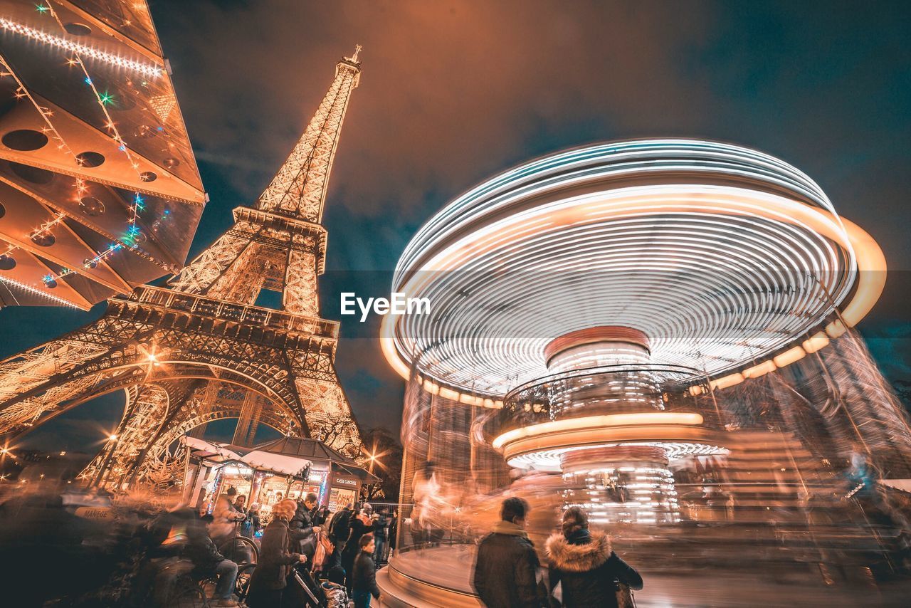 LOW ANGLE VIEW OF ILLUMINATED CAROUSEL AGAINST SKY AT NIGHT