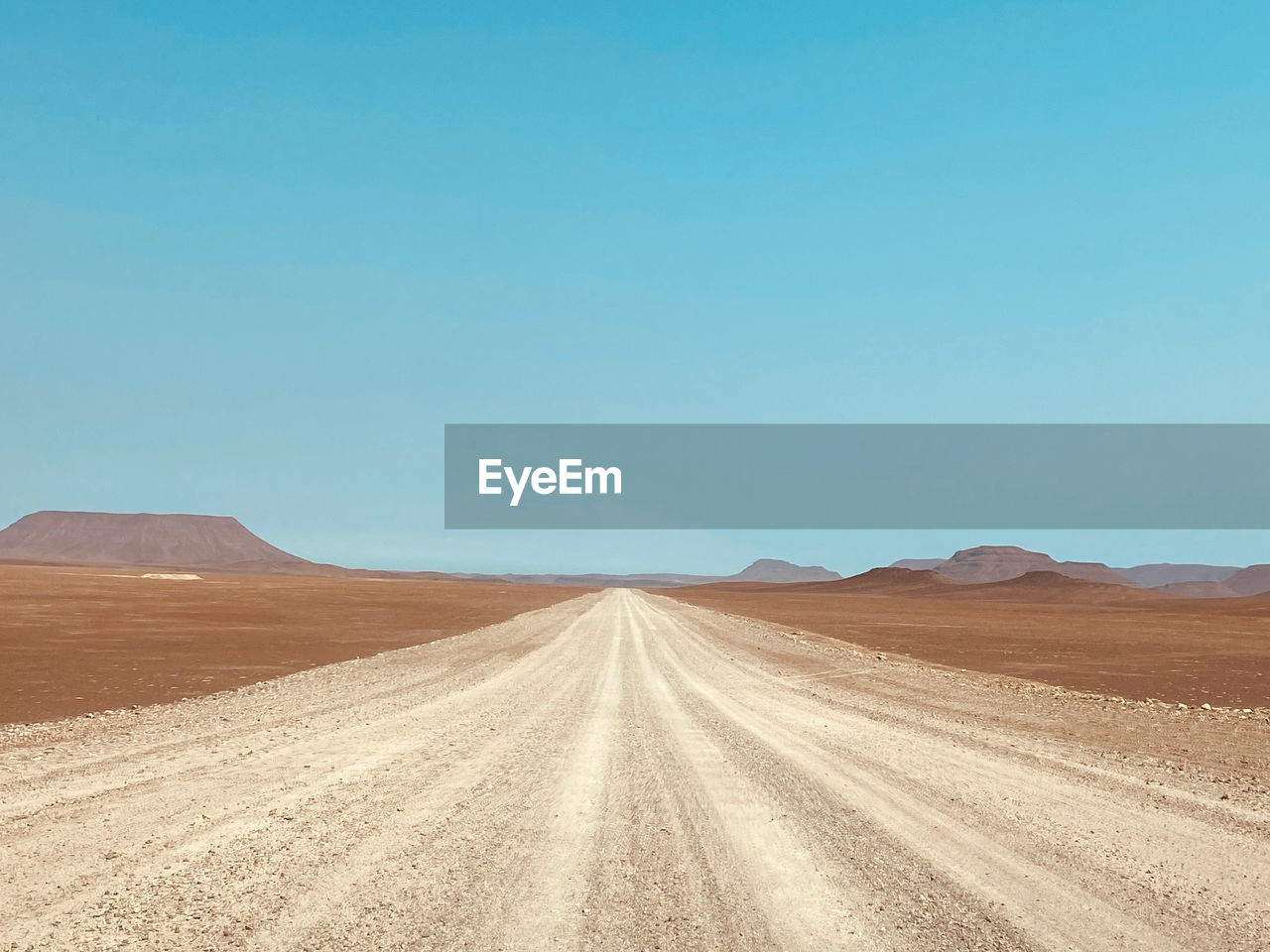 Scenic view of endless desert roads against clear blue sky