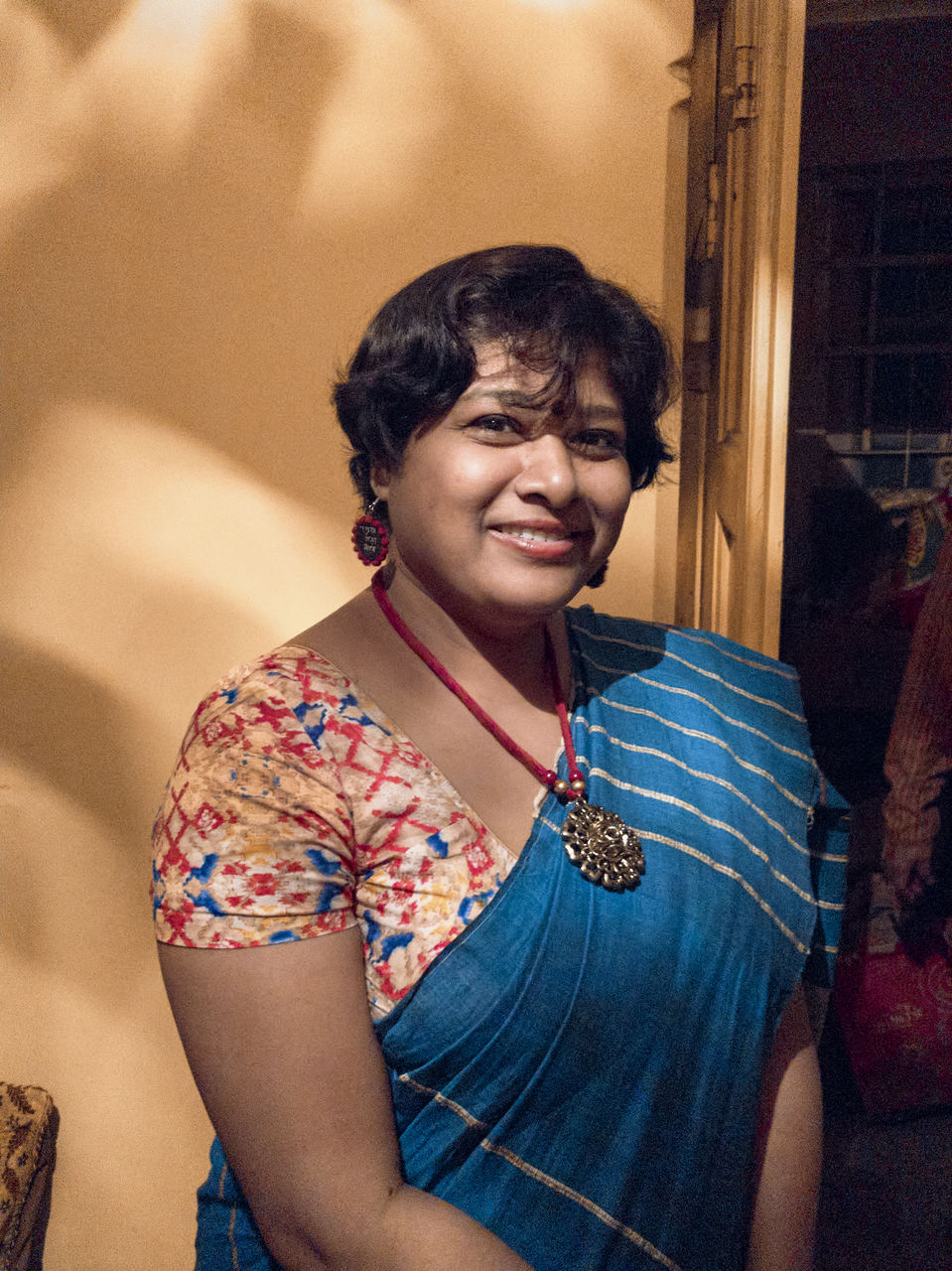 Indoor portrait of a smiling indian woman in fashionable sari, lit by incandescent warm lighting