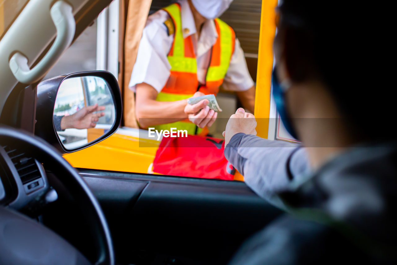 Cropped image of man paying at tollbooth from car