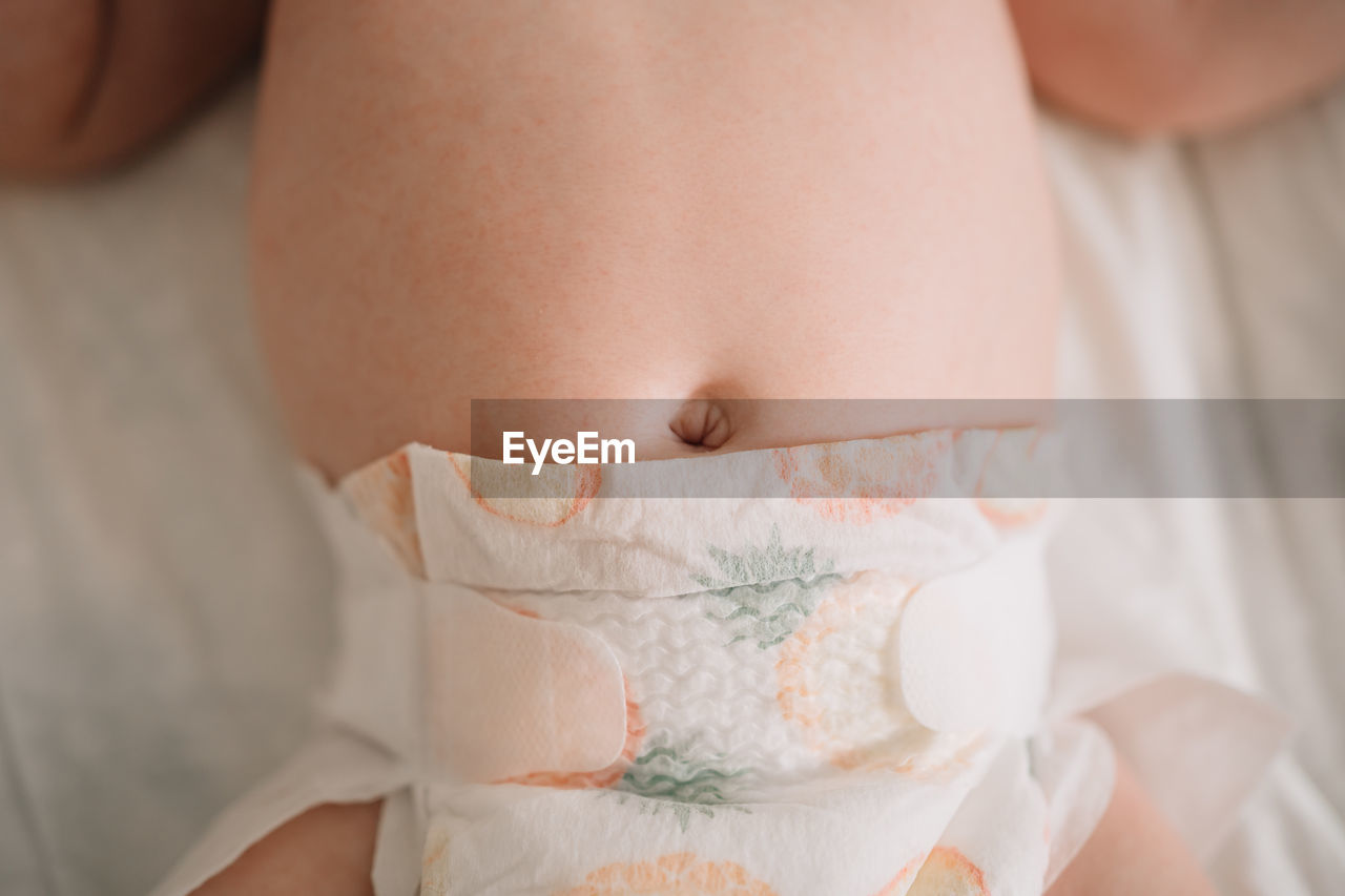 Midsection of baby lying down on bed