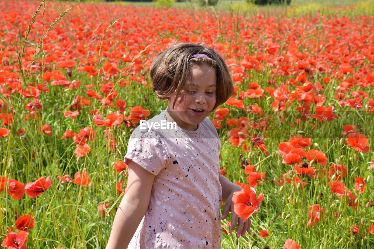 Portrait of woman standing amidst yellow flowering plants on field