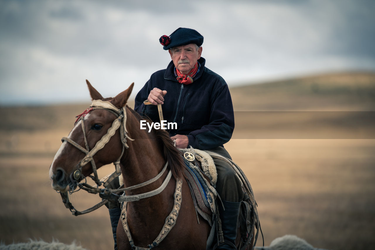 YOUNG MAN RIDING HORSE ON FIELD