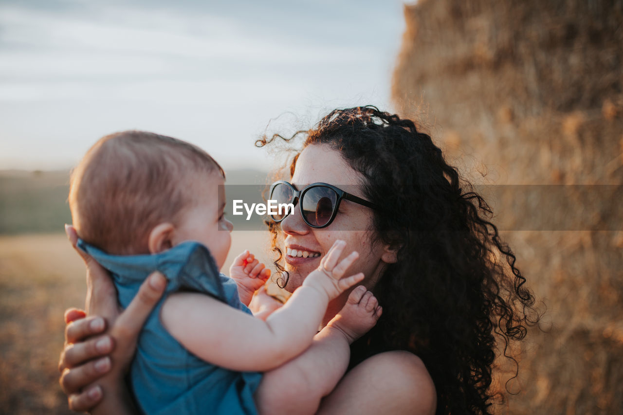 Close-up of mother carrying daughter against sky