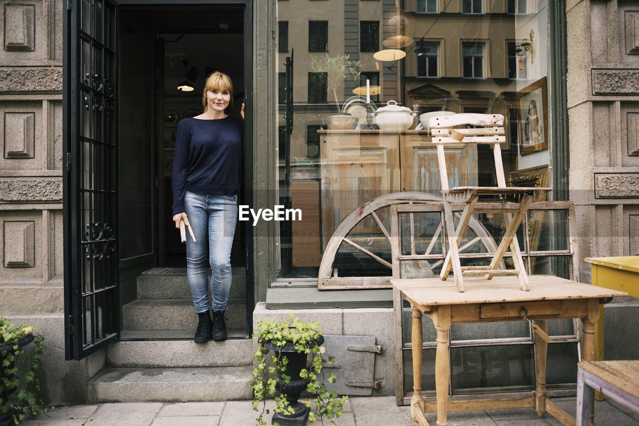 Female owner standing on entrance of antique shop