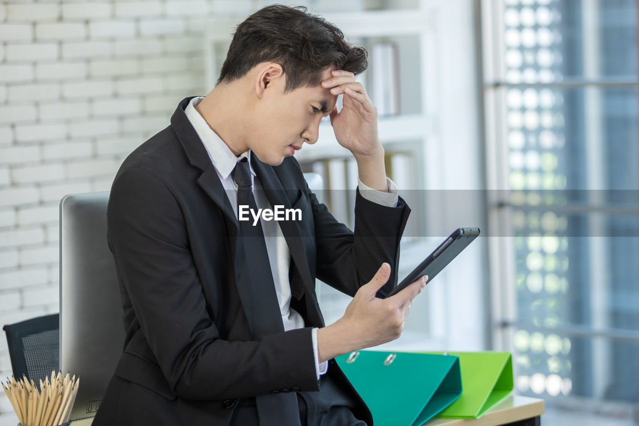 YOUNG MAN USING MOBILE PHONE IN OFFICE