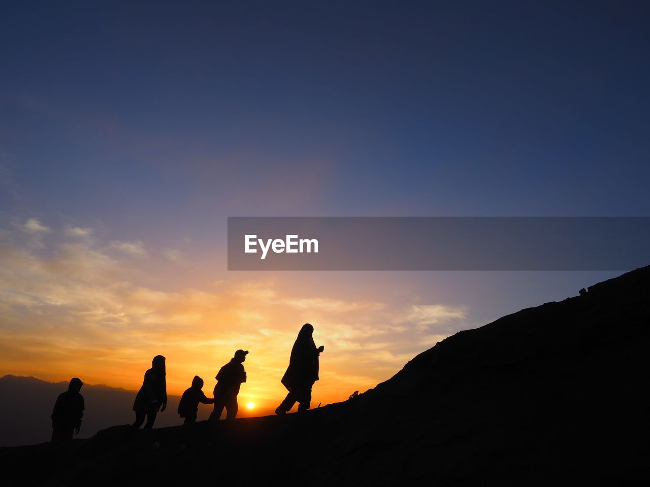 Silhouette people standing on mountain against sky during sunrise