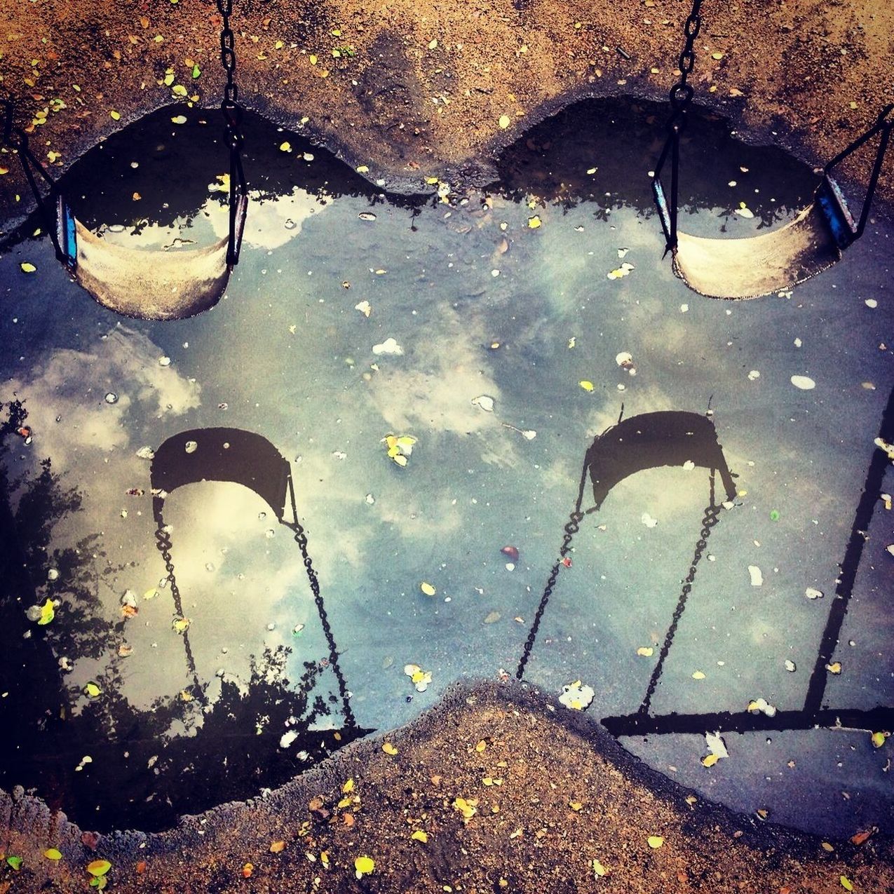 Reflection of swing in puddle on street