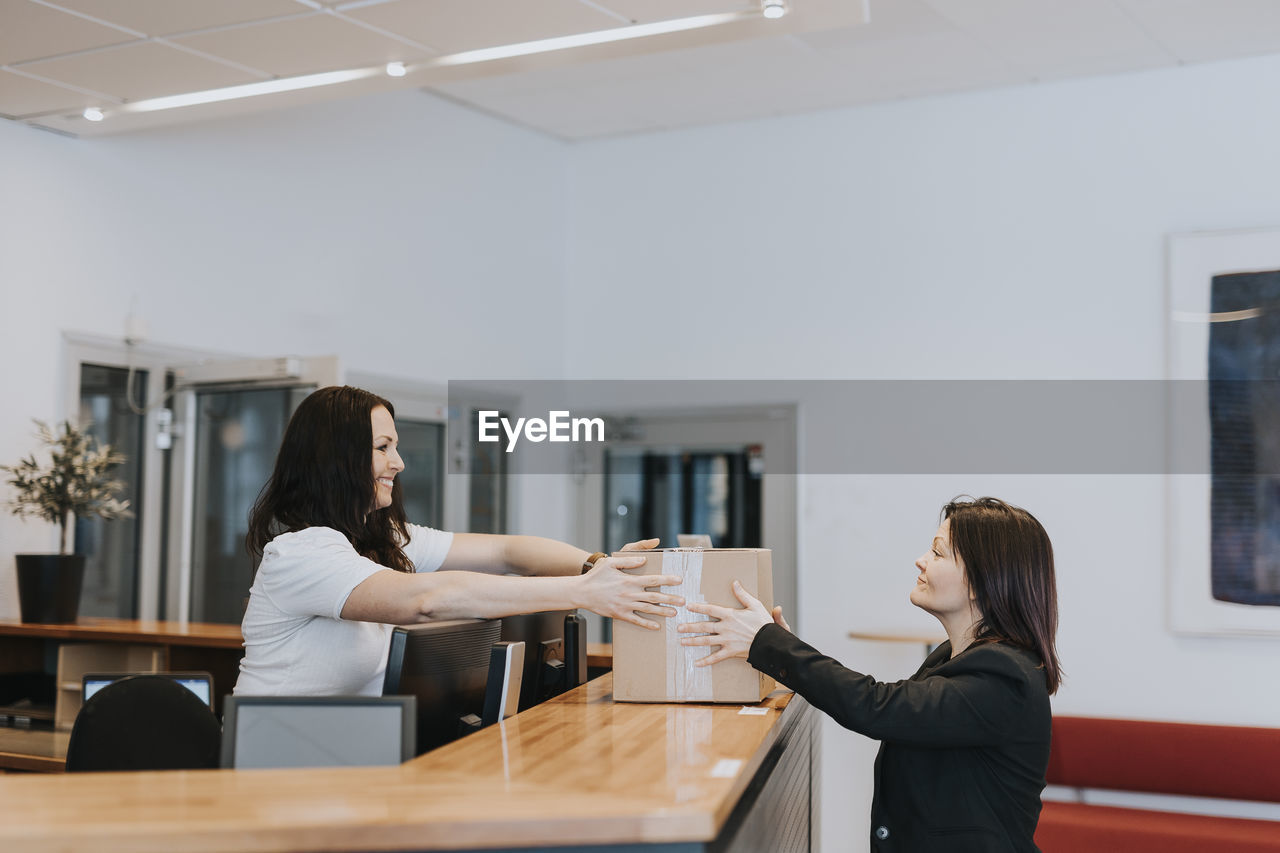 Smiling woman with cardboard box in office