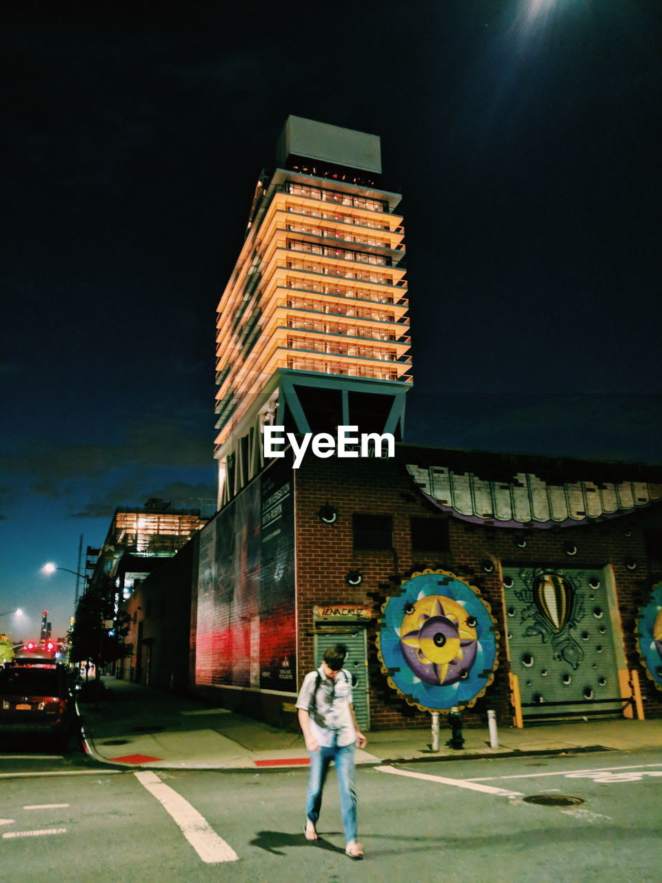 FULL LENGTH OF WOMAN STANDING ON STREET AGAINST ILLUMINATED BUILDINGS