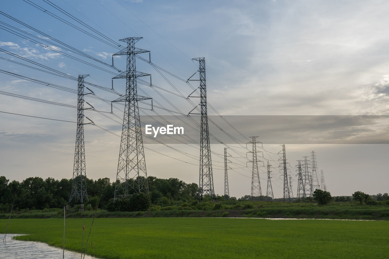 Low angle view of electricity pylon on field against sky