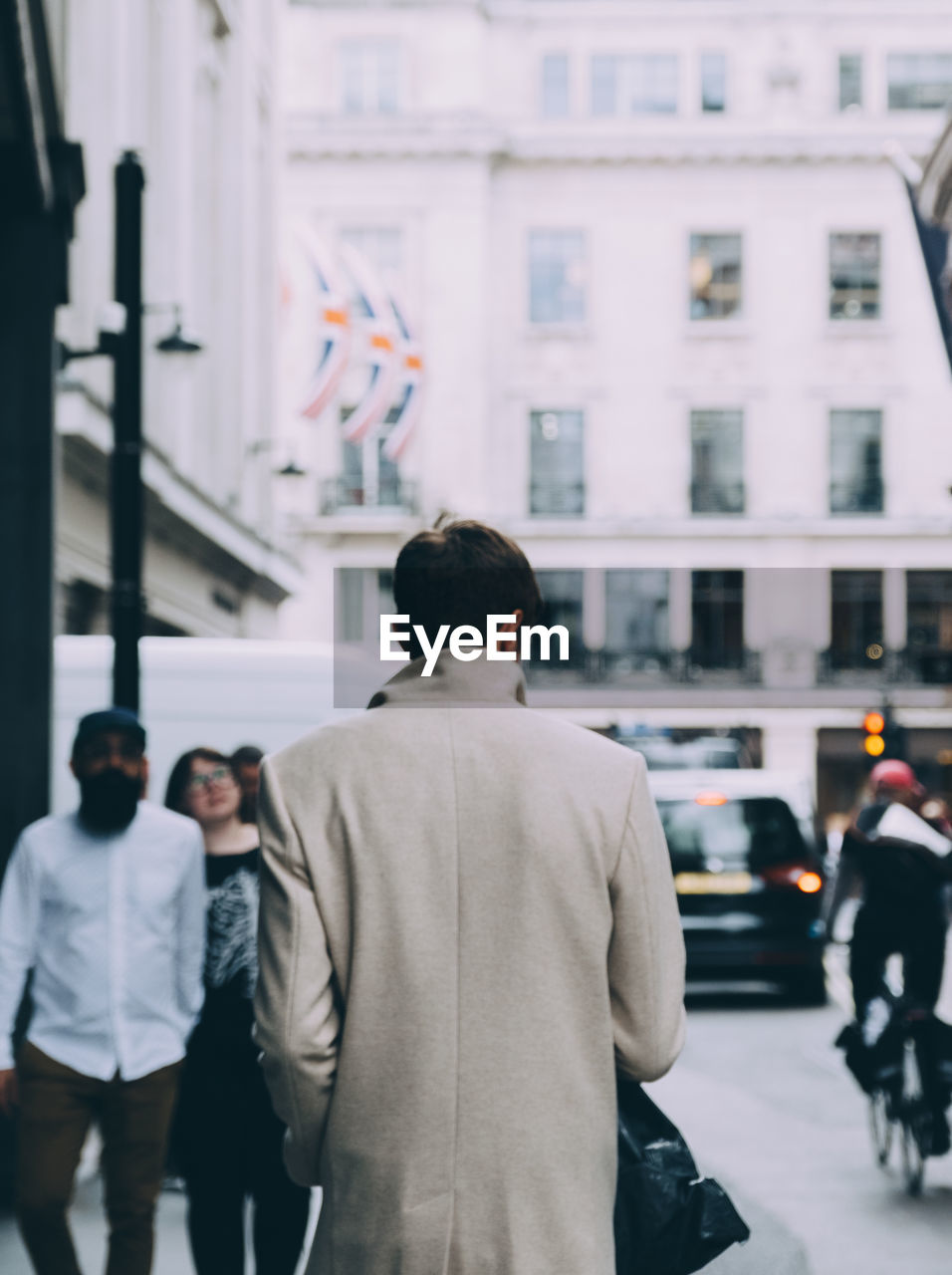 Rear view of people walking on street in city