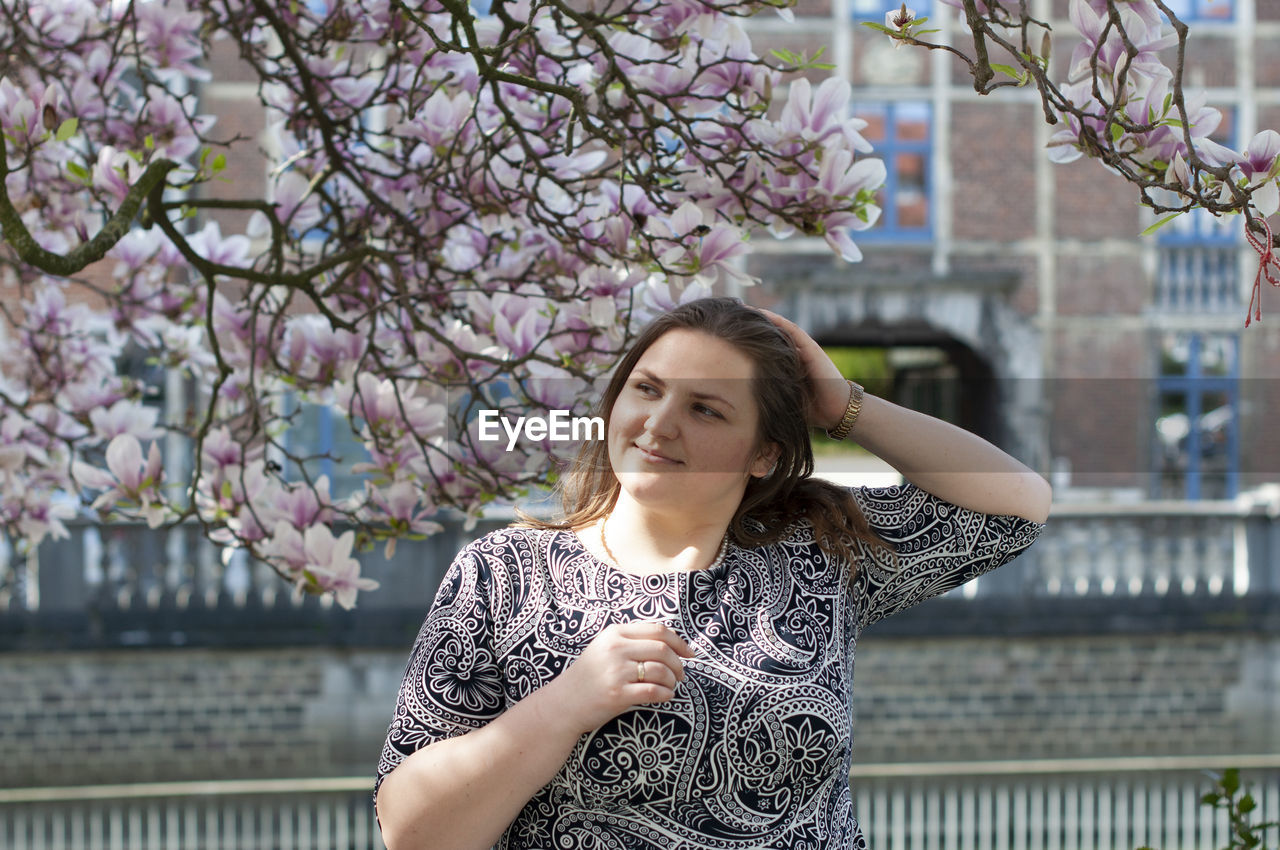 Portrait of a beautiful plump caucasian confident woman in magnolia flowers