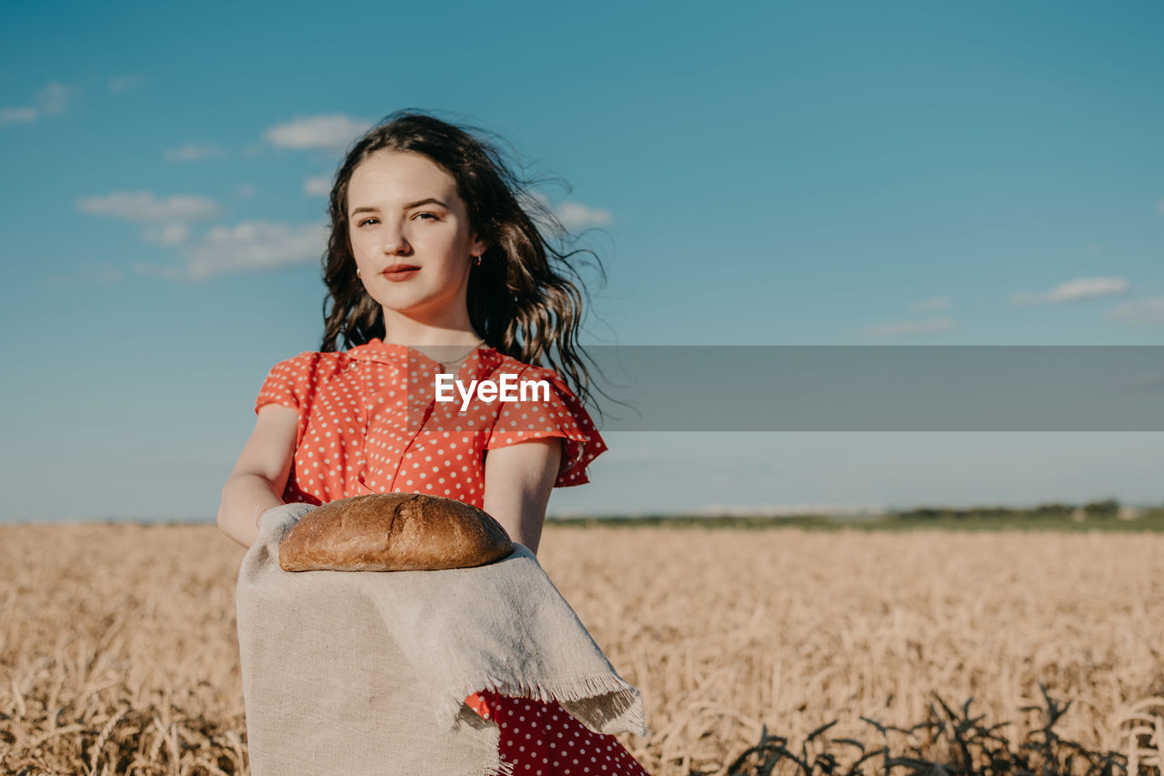 Portrait of woman standing on field against sky