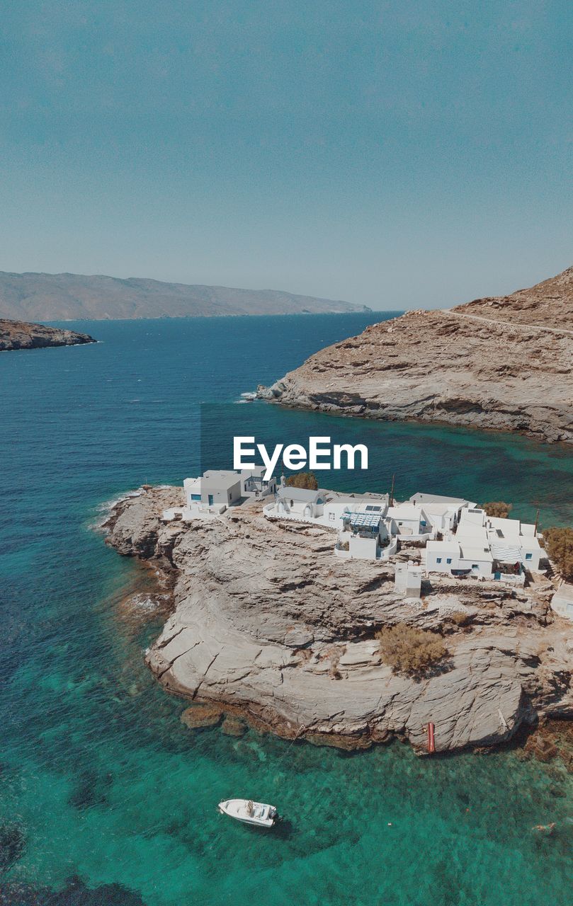 Drone photo of a secret place in tinos white traditional blue and white houses near the sea.