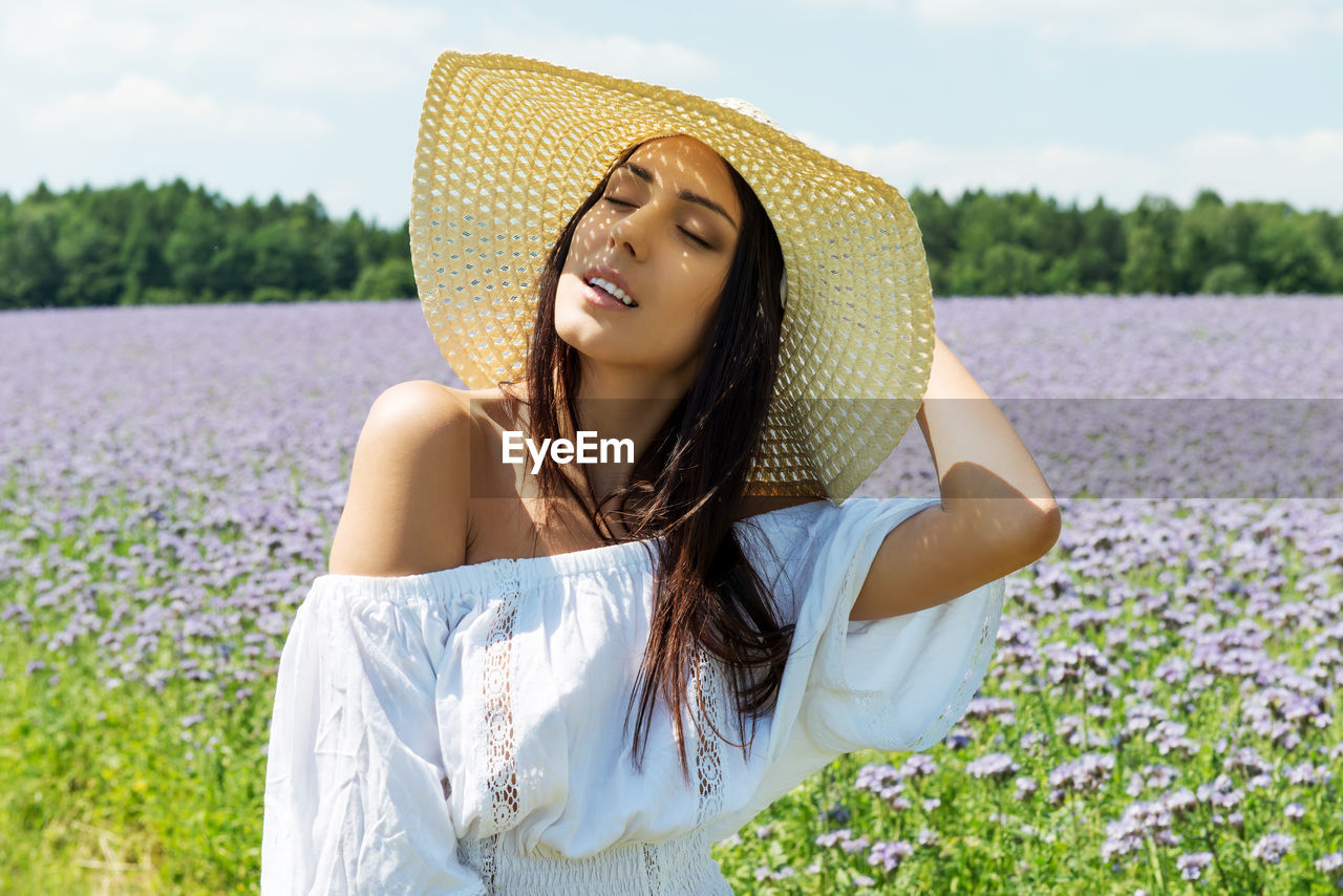 Woman in sun hat standing on field against sky