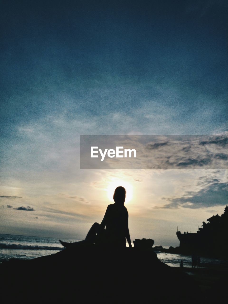 Silhouette of woman sitting on beach