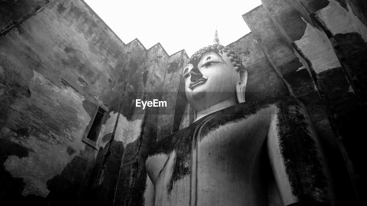 LOW ANGLE VIEW OF STATUE AGAINST TEMPLE