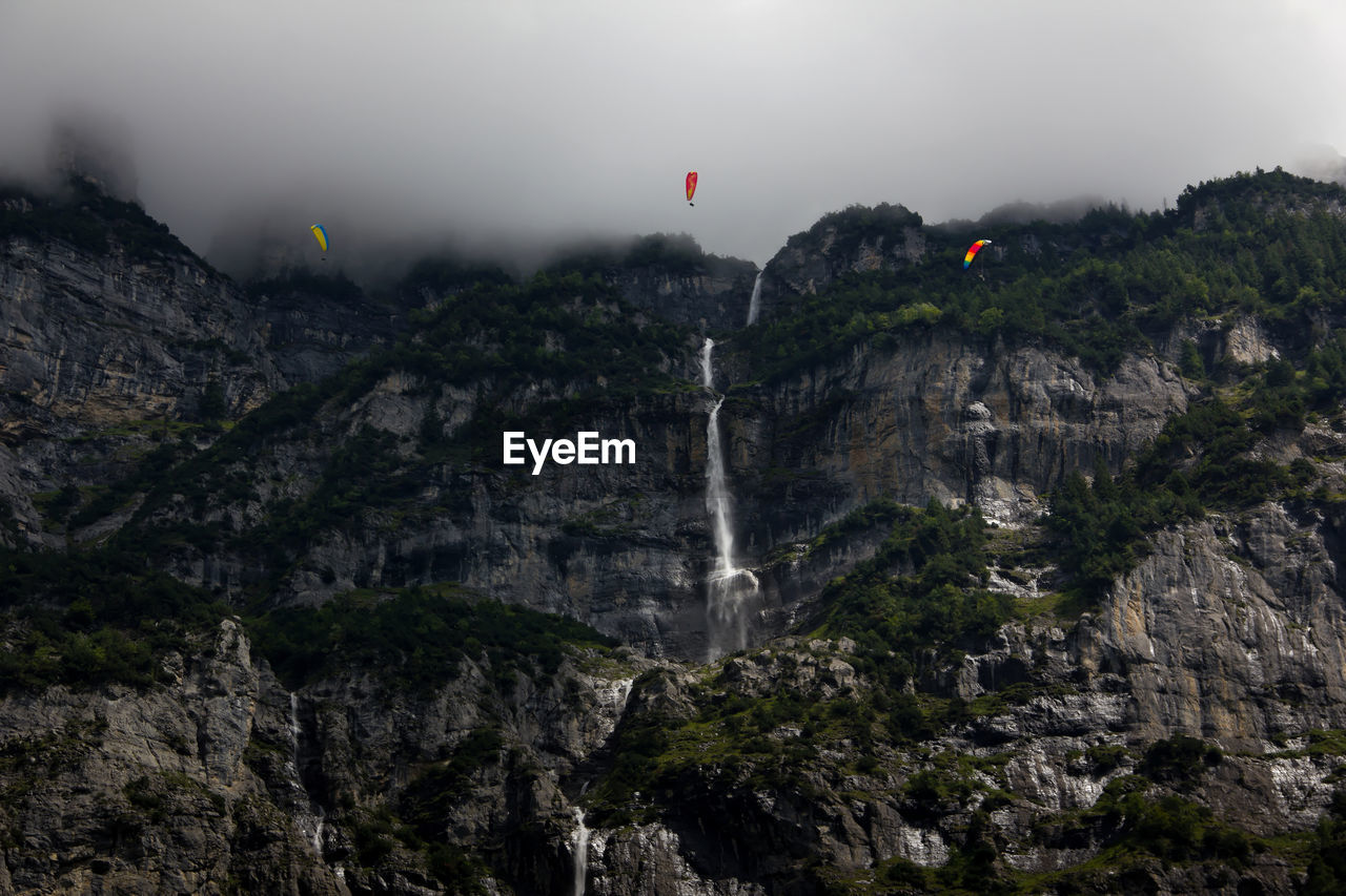 Low angle view of waterfall against sky during foggy weather