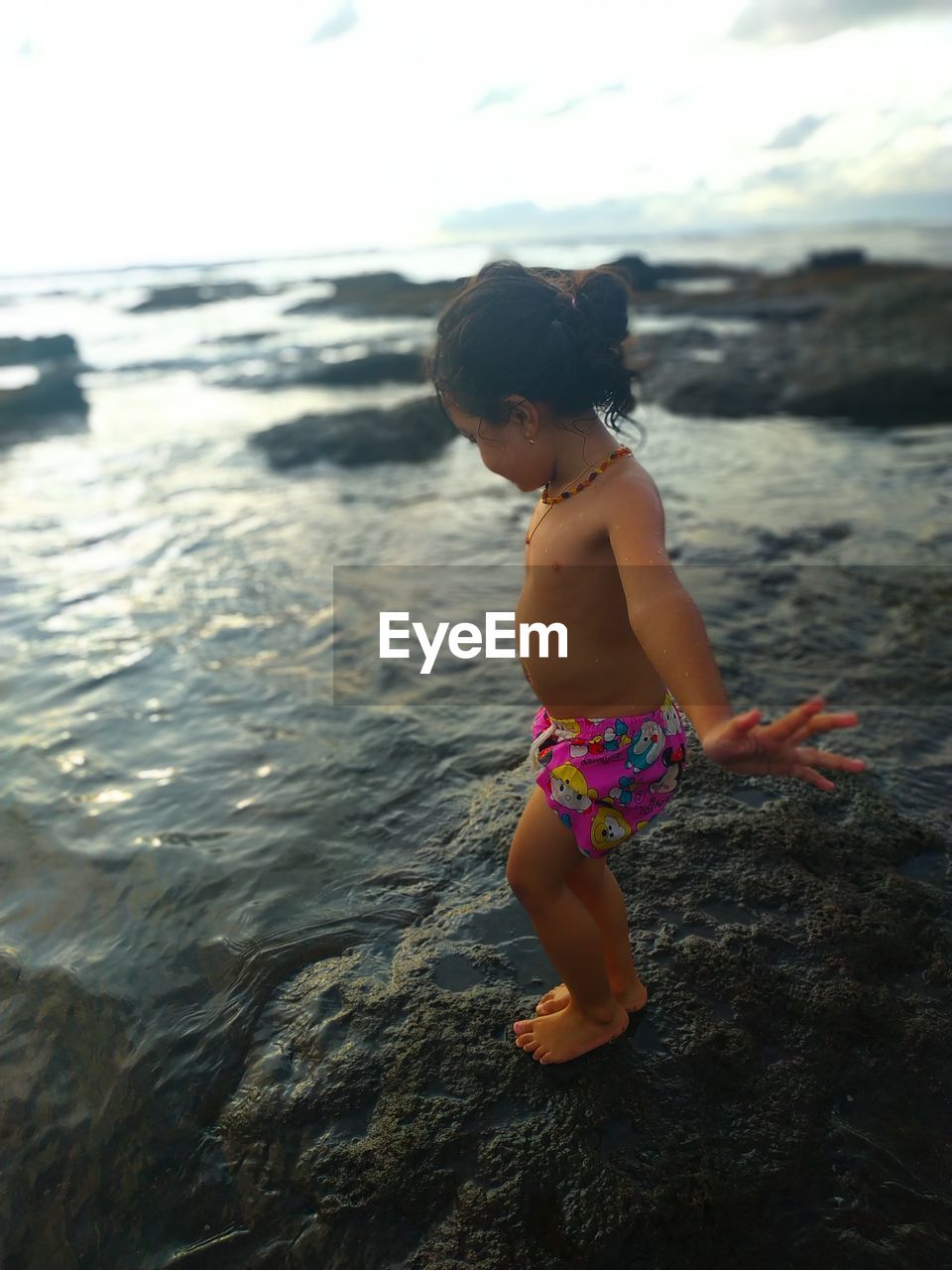 rear view of woman standing in sea against sky