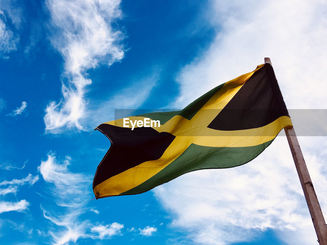 Low angle view of jamaican flag against sky