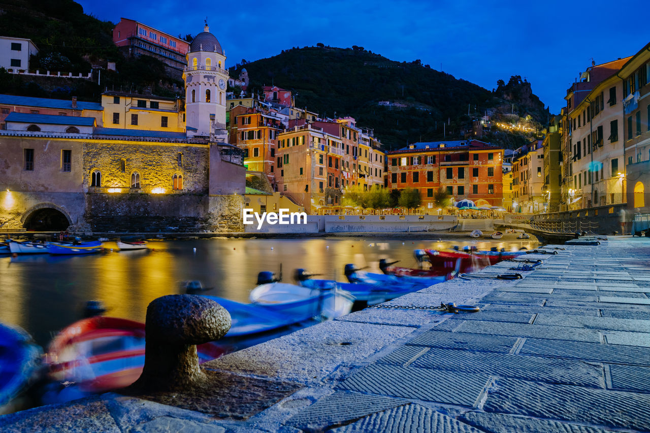 BOATS IN CANAL AMIDST BUILDINGS AT NIGHT