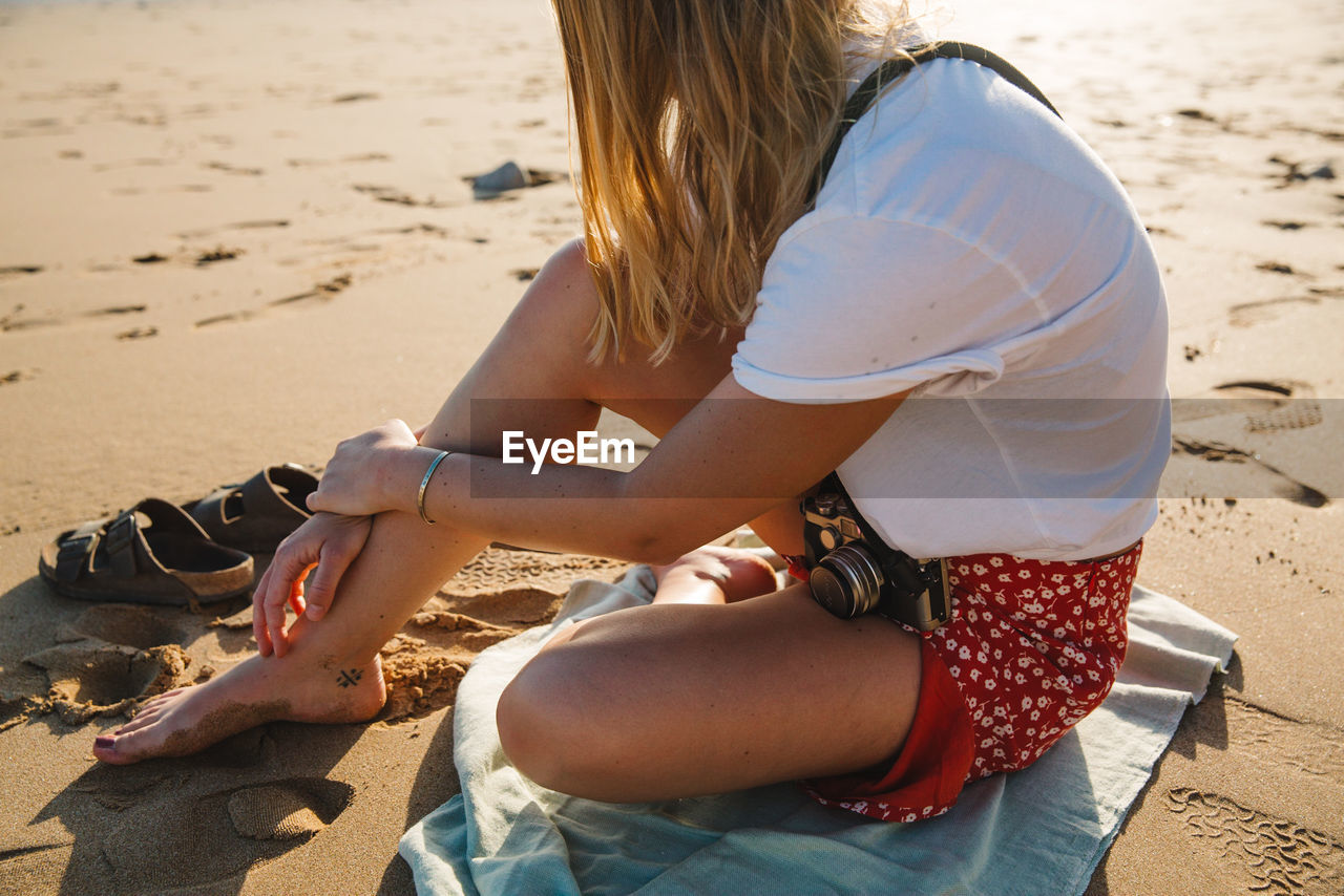 Woman sitting on sand at beach